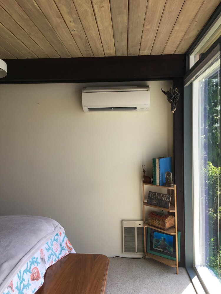 ductless heat pump in room by dark wood panel